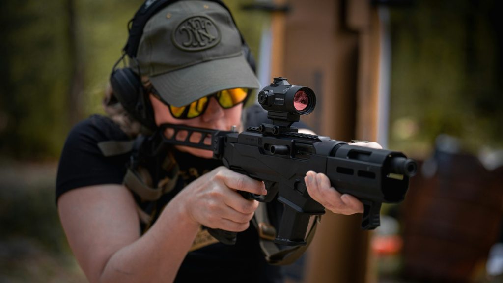 A woman wearing a hat and holding a gun